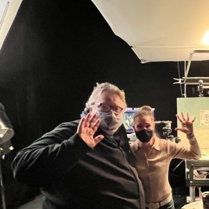 Deux personnes masquées se tiennent sur le plateau de tournage d'un film et font signe à la caméra