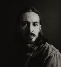 Portrait noir et blanc d'un homme aux cheveux longs portant une chemise boutonnée