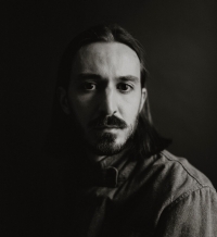 Portrait noir et blanc d'un homme aux cheveux longs portant une chemise boutonnée
