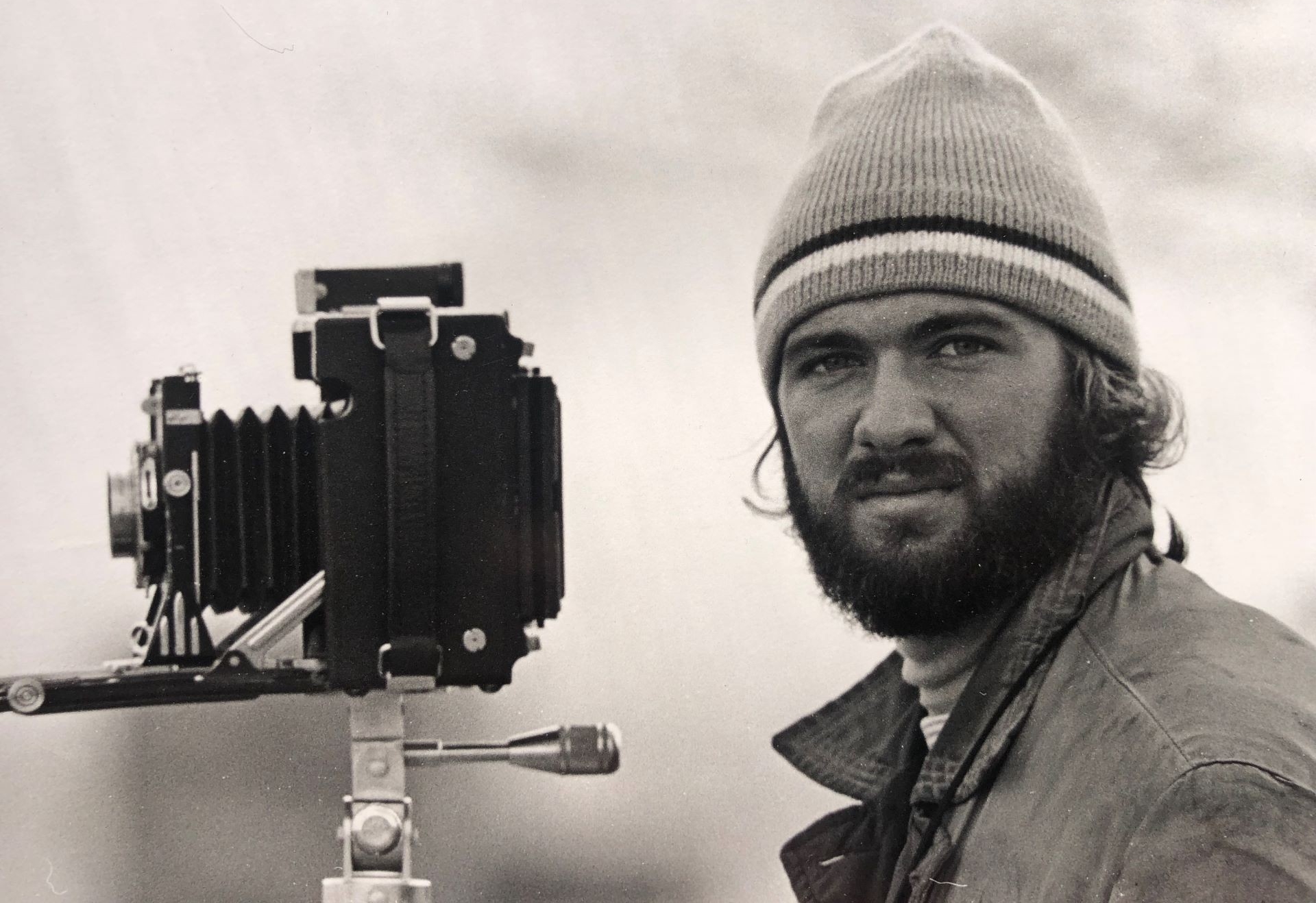 portrait en noir et blanc d'un jeune homme portant une tuque avec un appareil photo pliable