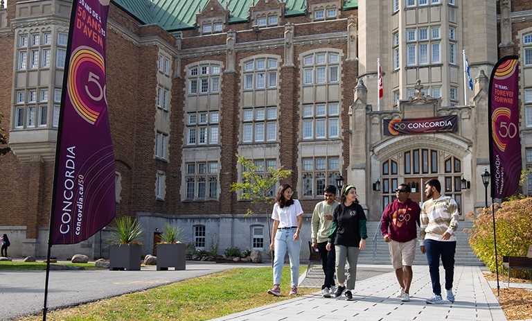 Les étudiants de Concordia sur le campus de Loyola Cinq étudiants de Concordia portant des t-shirts à l'effigie du 50e anniversaire se dirigent vers nous devant le bâtiment administratif du campus de Loyola.