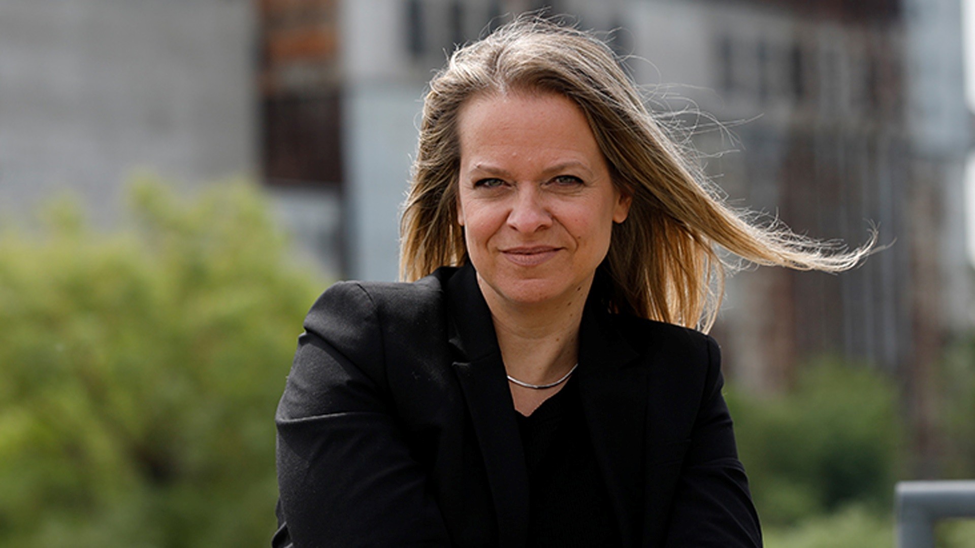 Photo de Natalie Voland Natalie a de longs cheveux blond foncé et pose à l'extérieur vêtue d'un chemisier foncé.