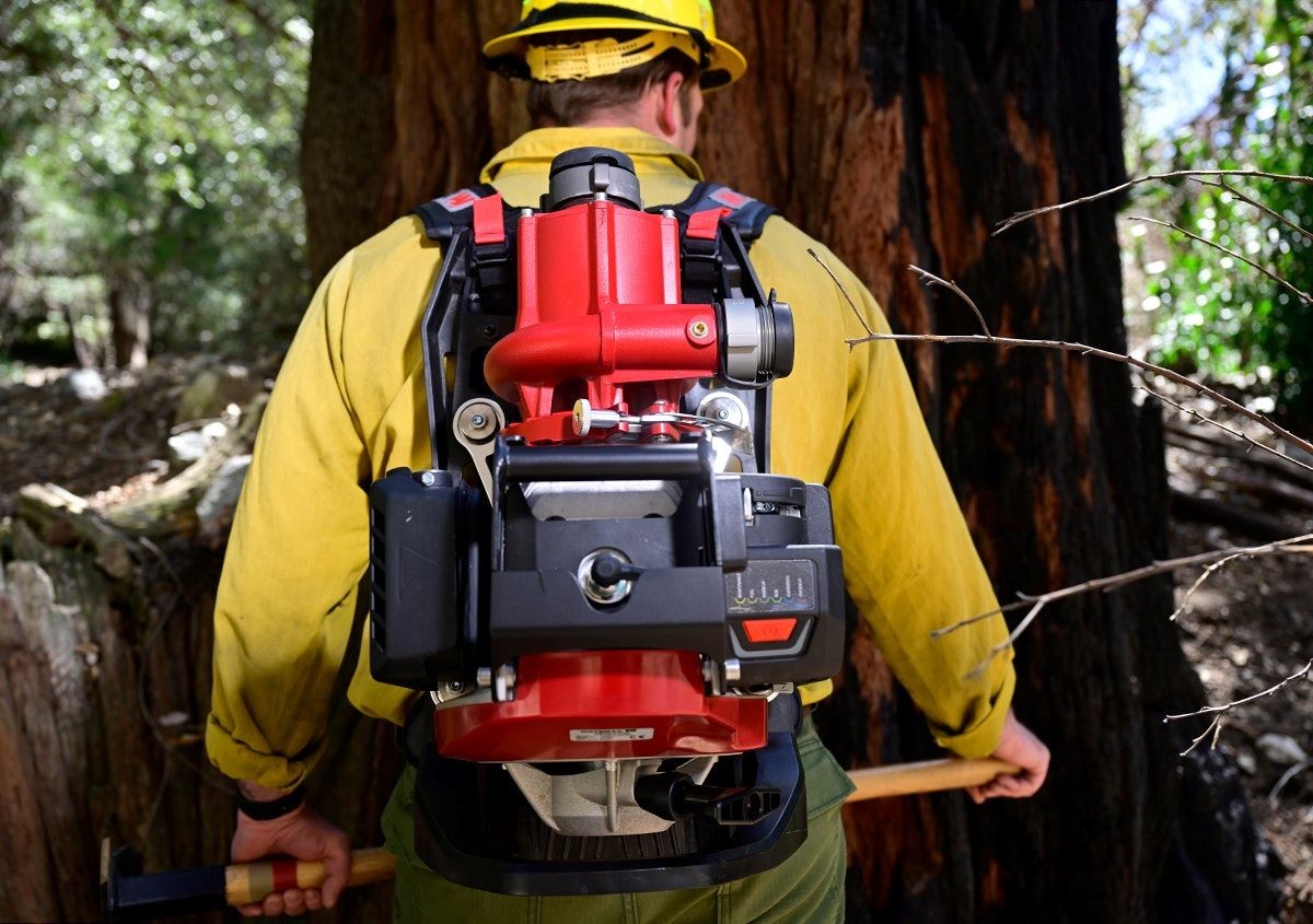 Un homme vêtu d'une veste jaune porte une pompe rouge attachée dans le dos.