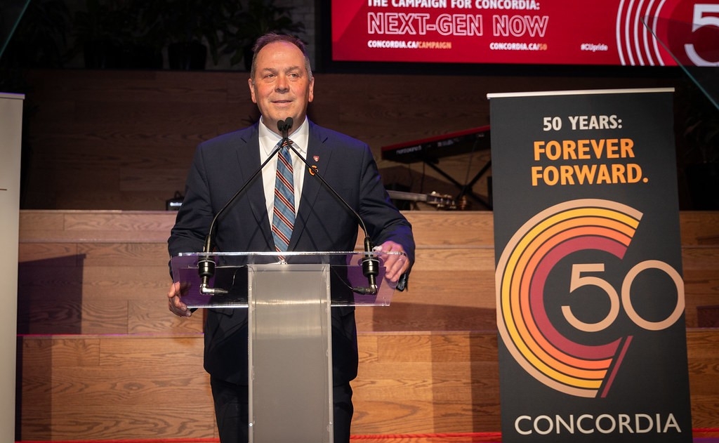Un homme en costume parle à un podium. 