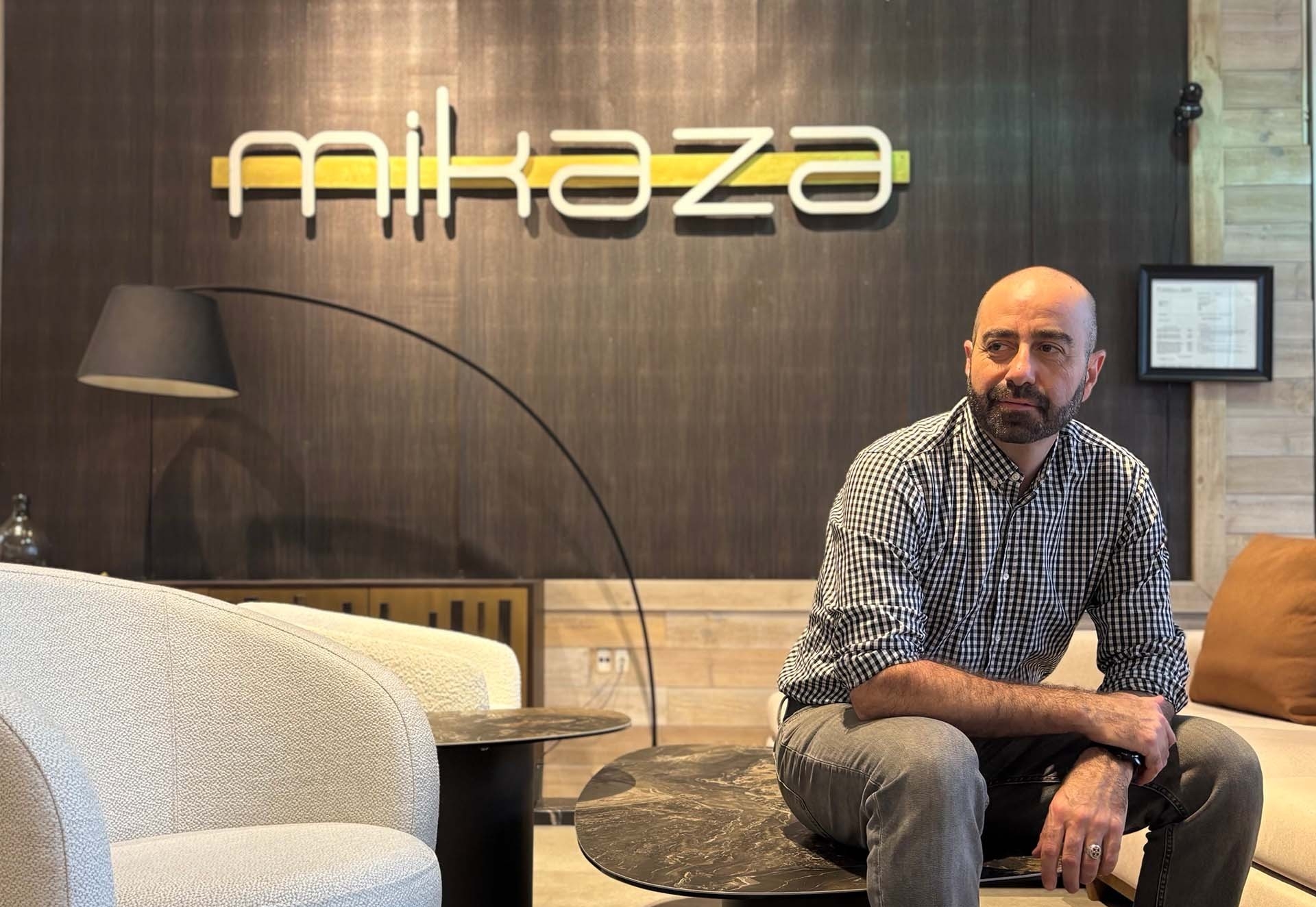 Mihran est assis sur une table basse sous une pancarte qui indique « Mikaza ».