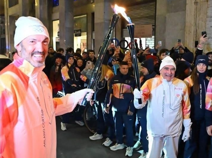 La flamme olympique est transférée entre les torches de deux porteurs. 