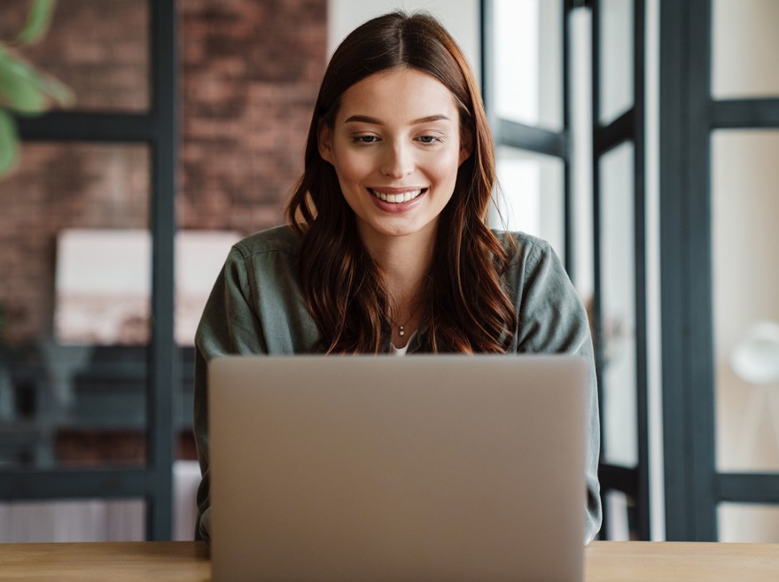 A woman smiles at her laptop