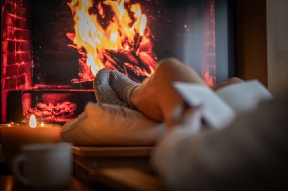 Une femme lit près du foyer.