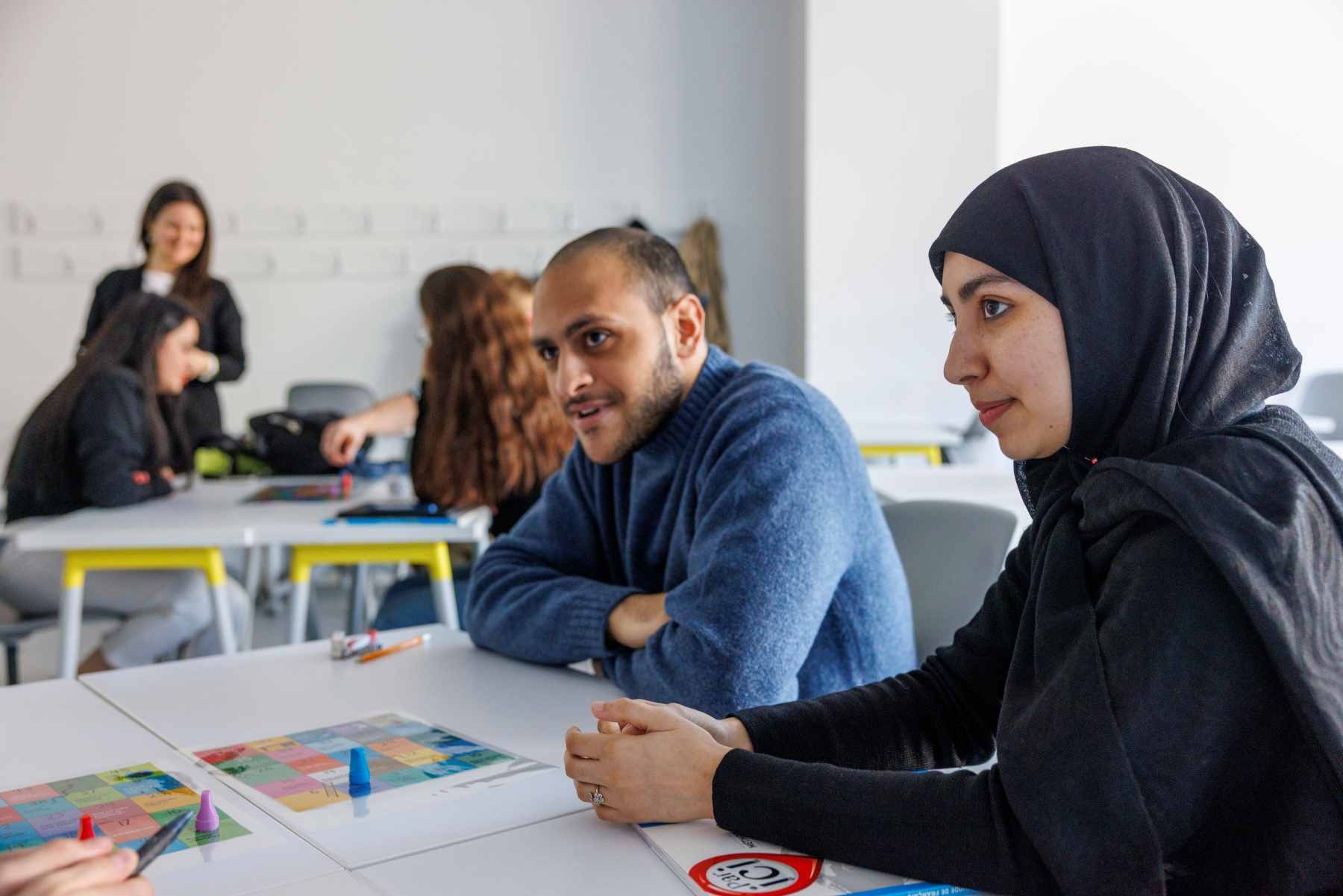 Deux étudiants assis à un bureau écoutent attentivement.