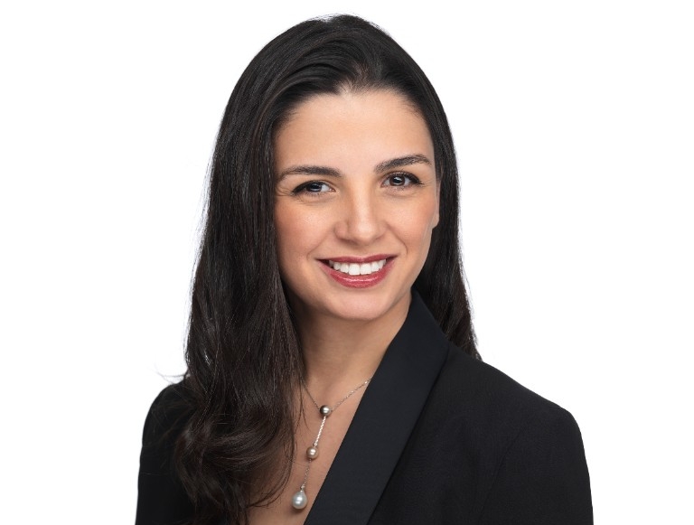 Yasmine Sardouk Femme souriante portant un blazer noir et un collier pendentif
