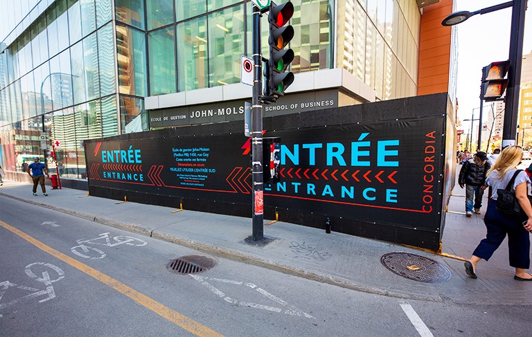 City street with pedestrians and a sign-board saying "entrance."