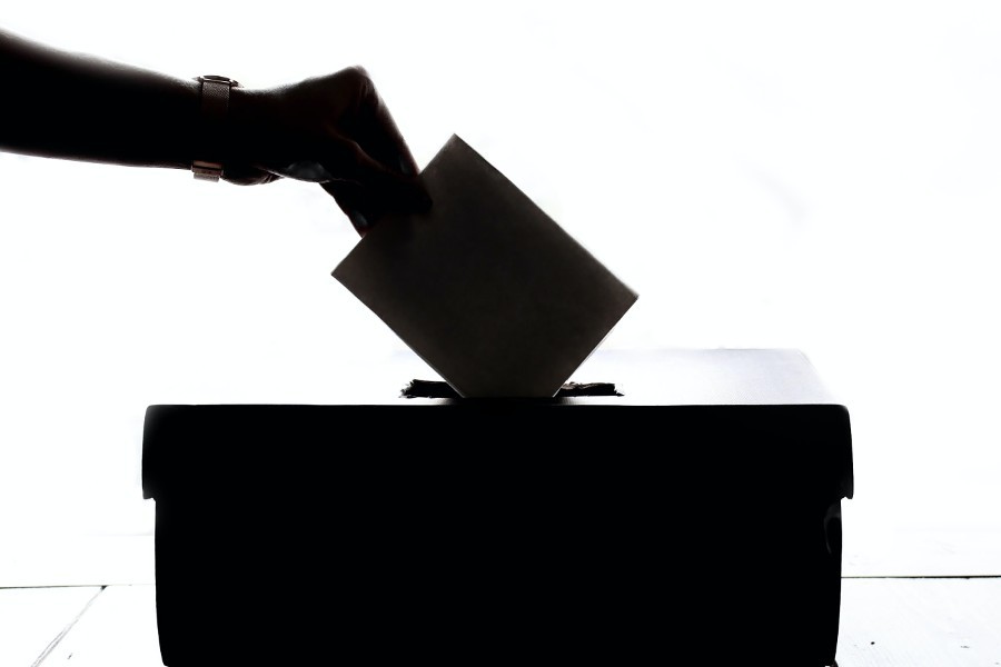 Silhouette d'une main qui insère un bulletin de vote dans une boite de scrutin Silhouette d'une main qui insère un bulletin de vote dans une boite de scrutin