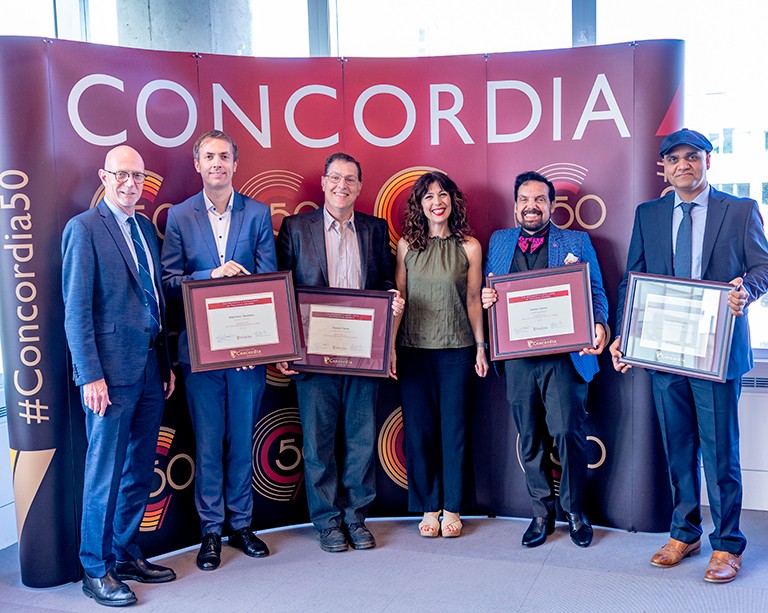 De gauche à droite : Graham Carr, recteur de Concordia, Matthäus Tekathen, Steven Henle, Sandra Gabriele, vice-rectrice exécutive adjointe à l’innovation en enseignement et en apprentissage, Aiman Hanna et Navneet Vidyarthi. Un groupe de personnes en tenue de soirée, debout dans une file d'attente et souriant à l'appareil photo.