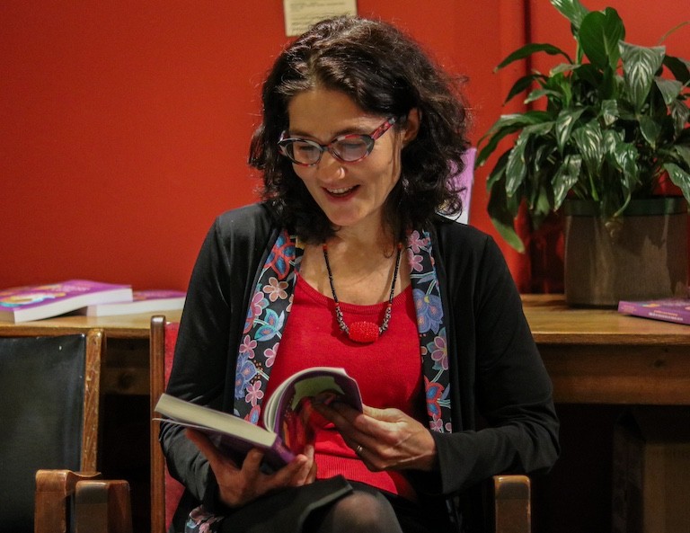 « Cet ouvrage explore la reconnexion culturelle, le partage des connaissances et la redéfinition de l’identité dans des contextes urbains et communautaires », explique Natasha Blanchet-Cohen. Une femme aux cheveux noirs et aux lunettes, assise sur une chaise, lisant un livre