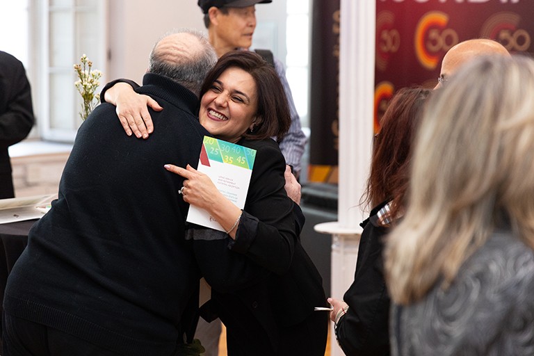 A smiling woman being hugged by a balding man.