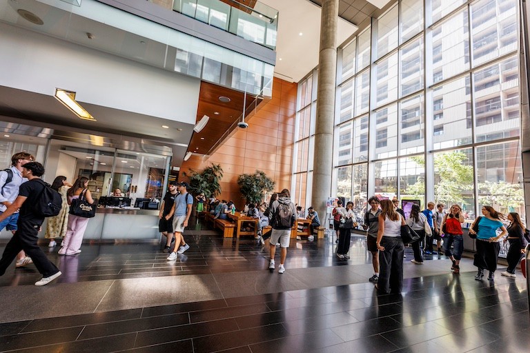  Grand atrium d'un bâtiment où des gens déambulent.